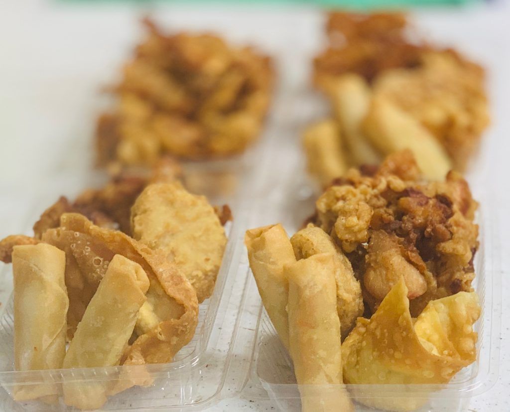 A close up of fried food in plastic containers on a table.