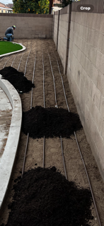 A pile of dirt is laying on the ground next to a fence.