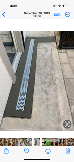 A phone screen shows a picture of a drain on a sidewalk.