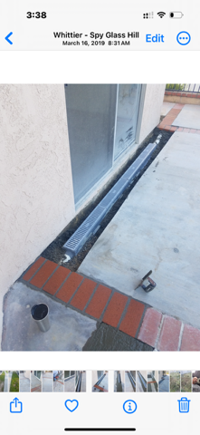 A phone screen shows a picture of a drain on the side of a building.