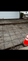 A concrete driveway is being built in front of a garage.