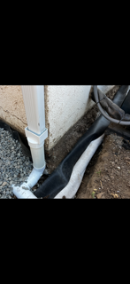 A drain pipe is being installed on the side of a house.
