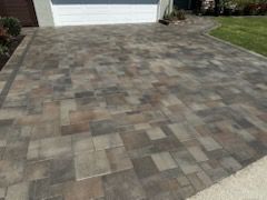 A brick driveway in front of a house with a garage door.