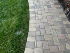 A brick walkway leading to a lush green lawn.