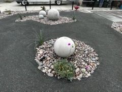 A garden with rocks and balls in the middle of it.