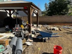 A wheelbarrow is sitting on the ground in front of a gazebo.