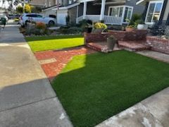 A front yard with a lush green lawn and a brick walkway.