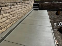 A concrete walkway is being built next to a brick wall.