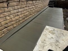 A concrete walkway next to a brick wall and stairs.