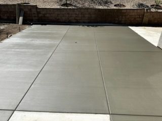 A concrete driveway with a brick wall in the background.