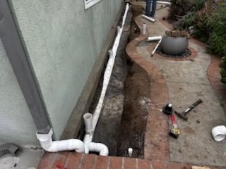 A drain pipe is being installed on the side of a house.