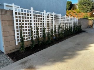 A white lattice fence surrounds a brick wall.