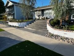 A house with stairs leading up to it and a sidewalk in front of it.