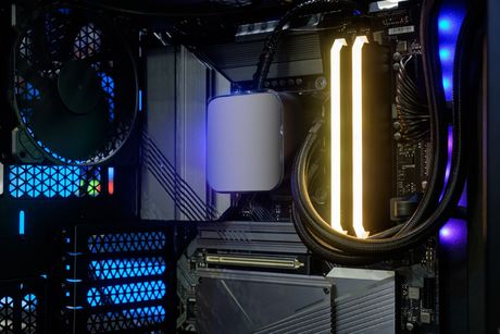 Inside a PC case with illuminated components: CPU cooler, RAM sticks, and fans.