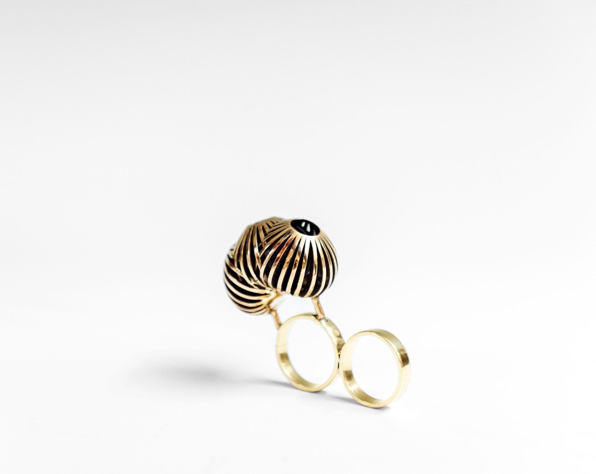 A gold ring with a black and white ball on it
