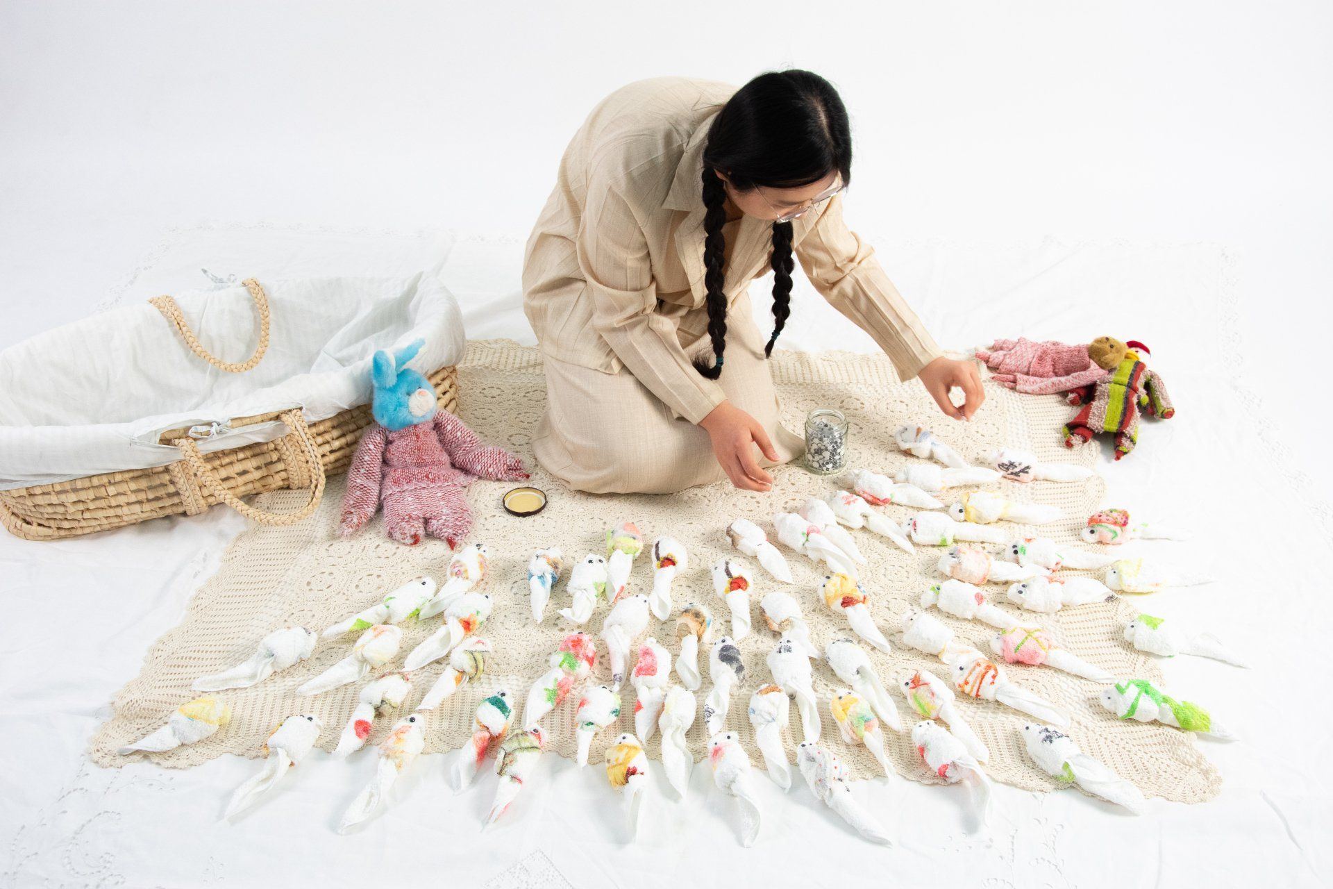 A woman is kneeling on the floor surrounded by toys