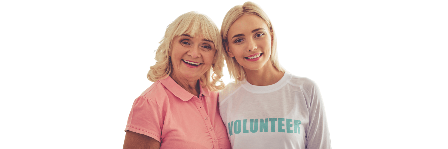 Two smiling volunteers standing together, one in a pink polo and one in a white volunteer T-shirt.