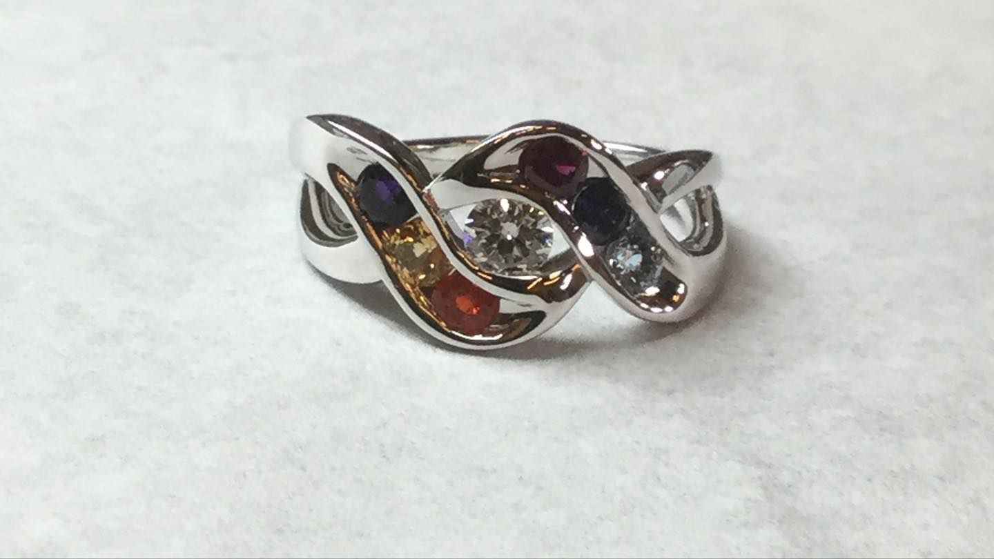 A silver ring with multicolored stones on a white surface
