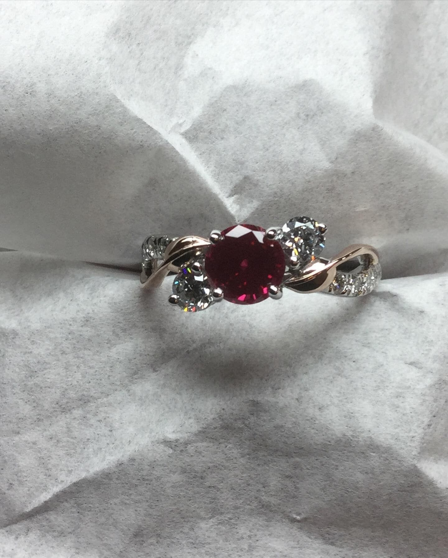 A close up of a ring with a ruby and diamonds