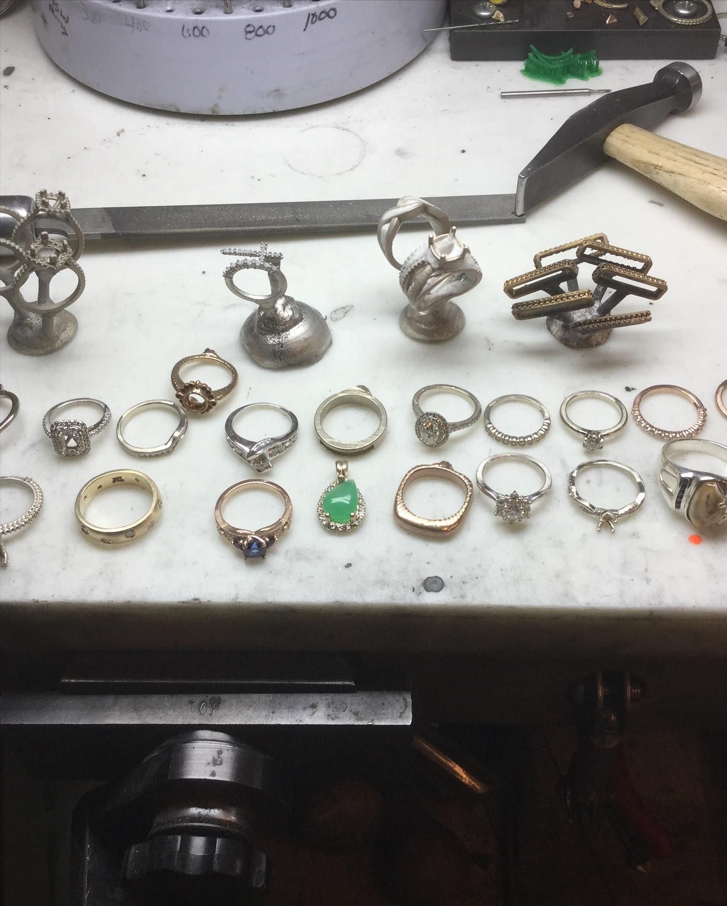A bunch of rings are on a table with a hammer