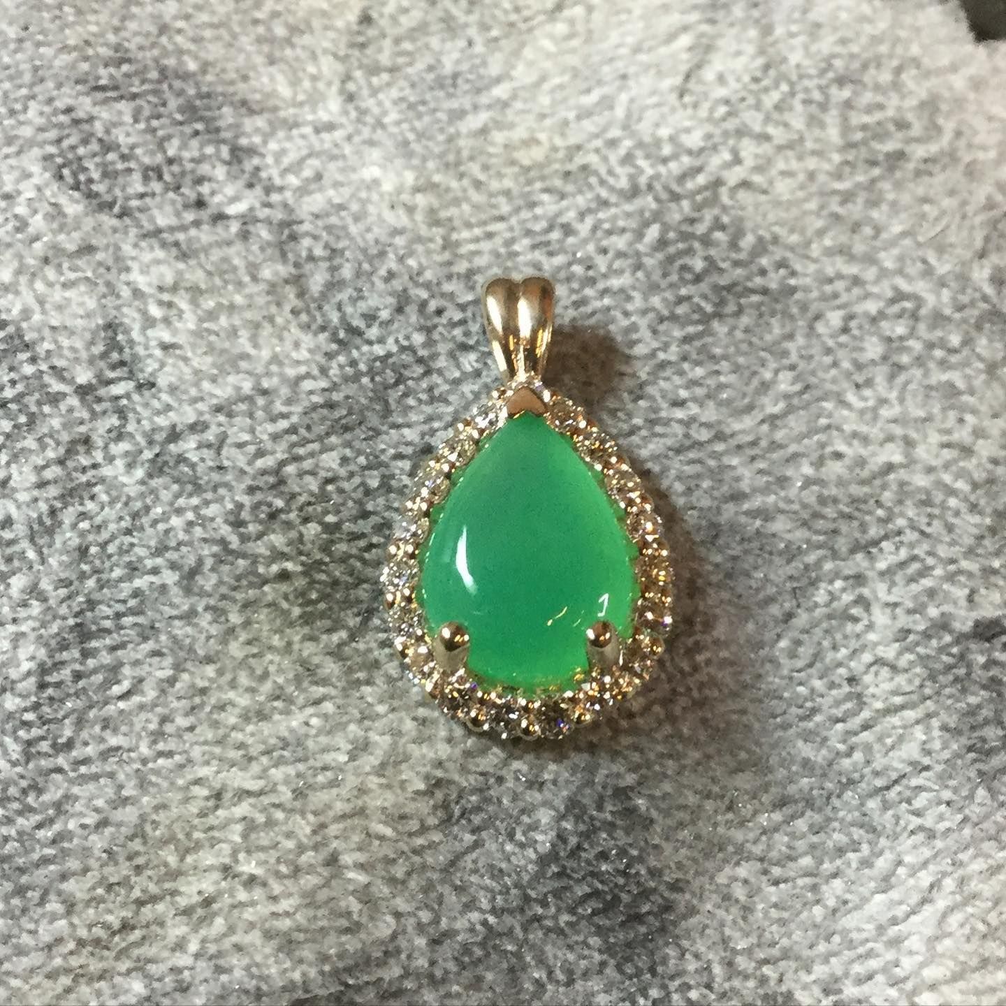 A gold pendant with a green stone in the center