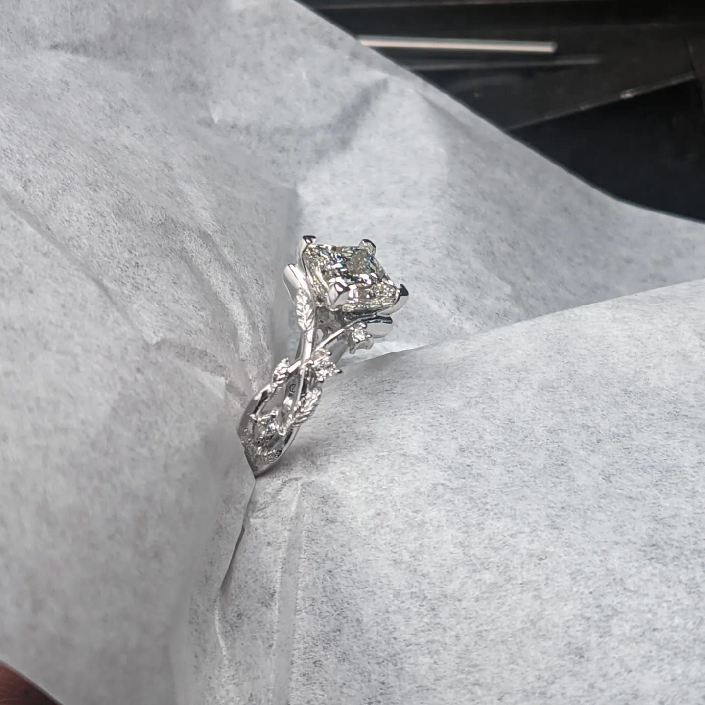 A diamond ring is sitting on top of a piece of paper.
