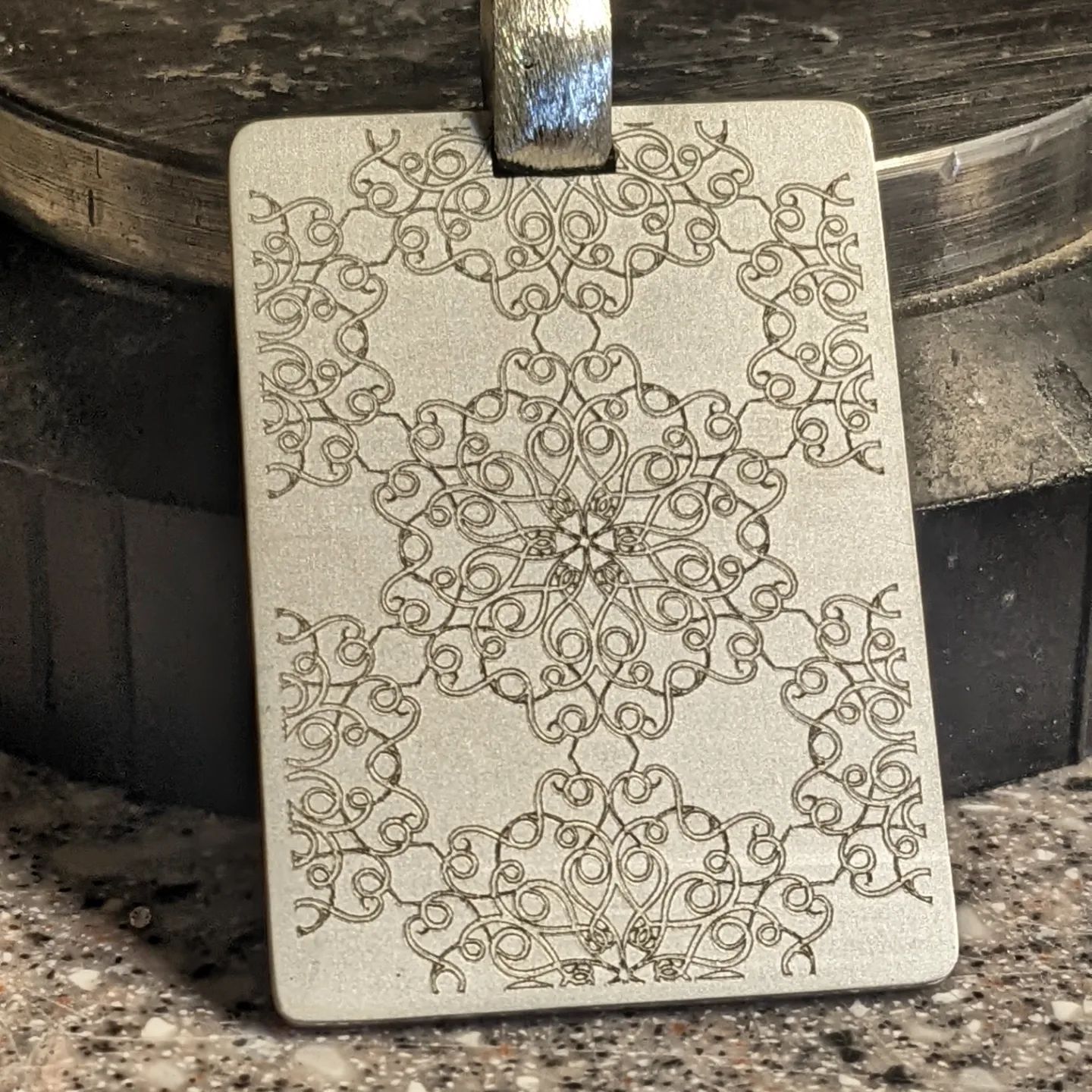 A silver pendant with a floral design on it