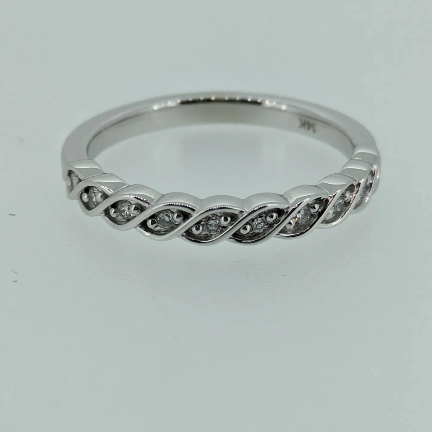 A silver ring with diamonds on a white surface