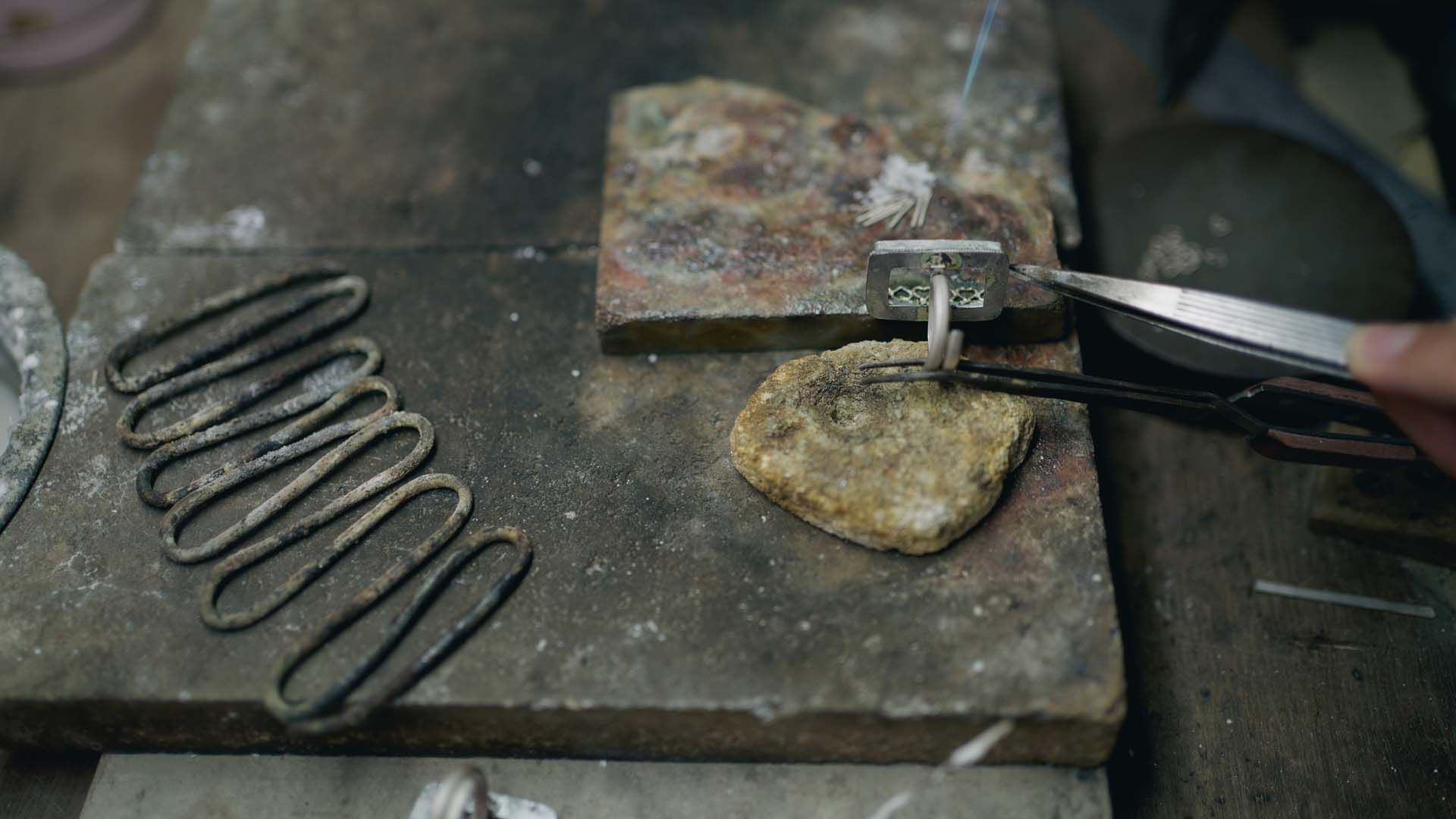 A person is working on a piece of metal on a table.