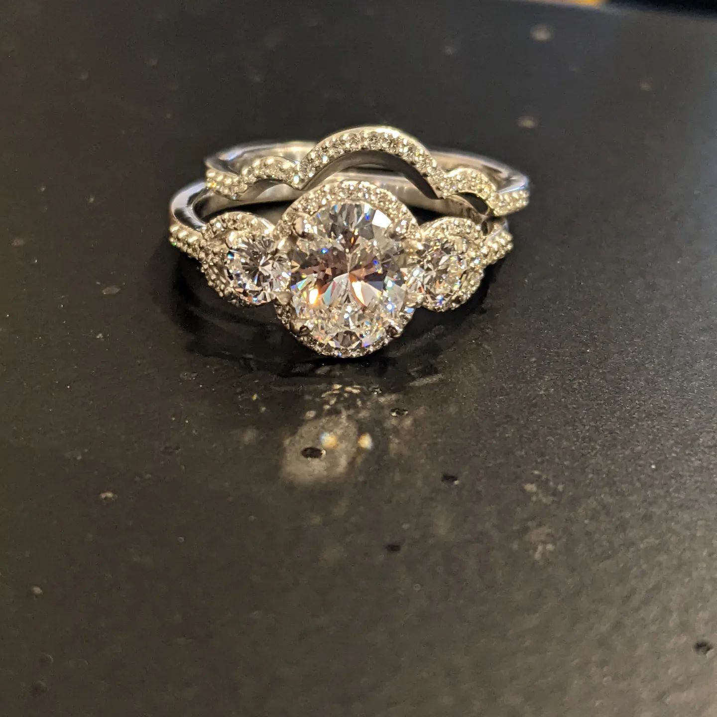 A diamond ring is sitting on a black surface.