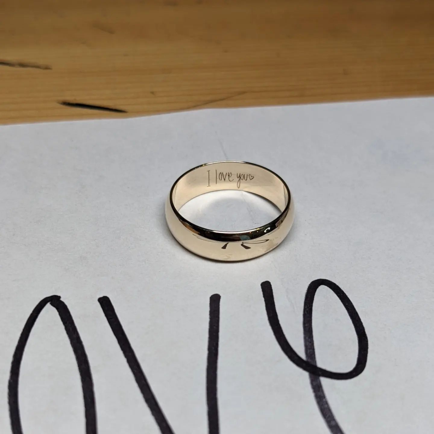 A gold ring sits on a piece of paper that says love