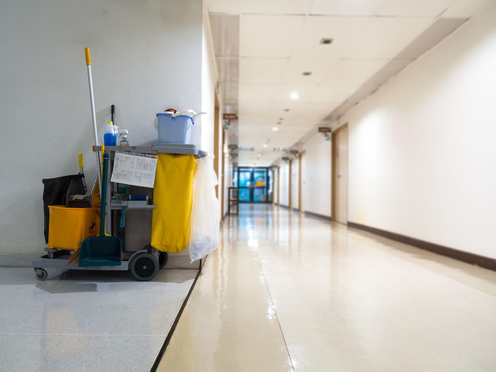 A janitorial cart with cleaning supplies sits in the corner of a long.