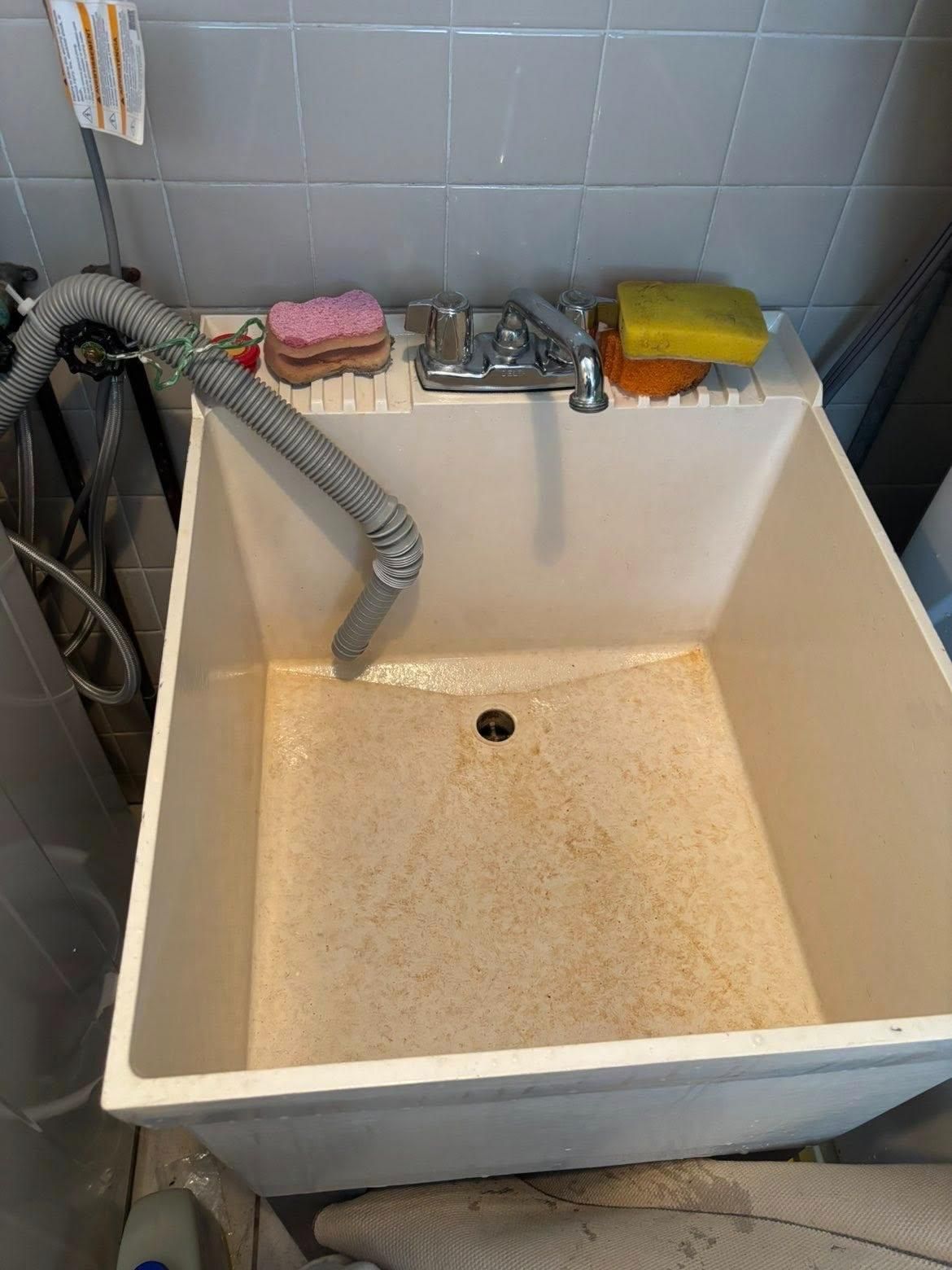 After cleaning a utility sink with a drain hose, faucet, and cleaning sponges.