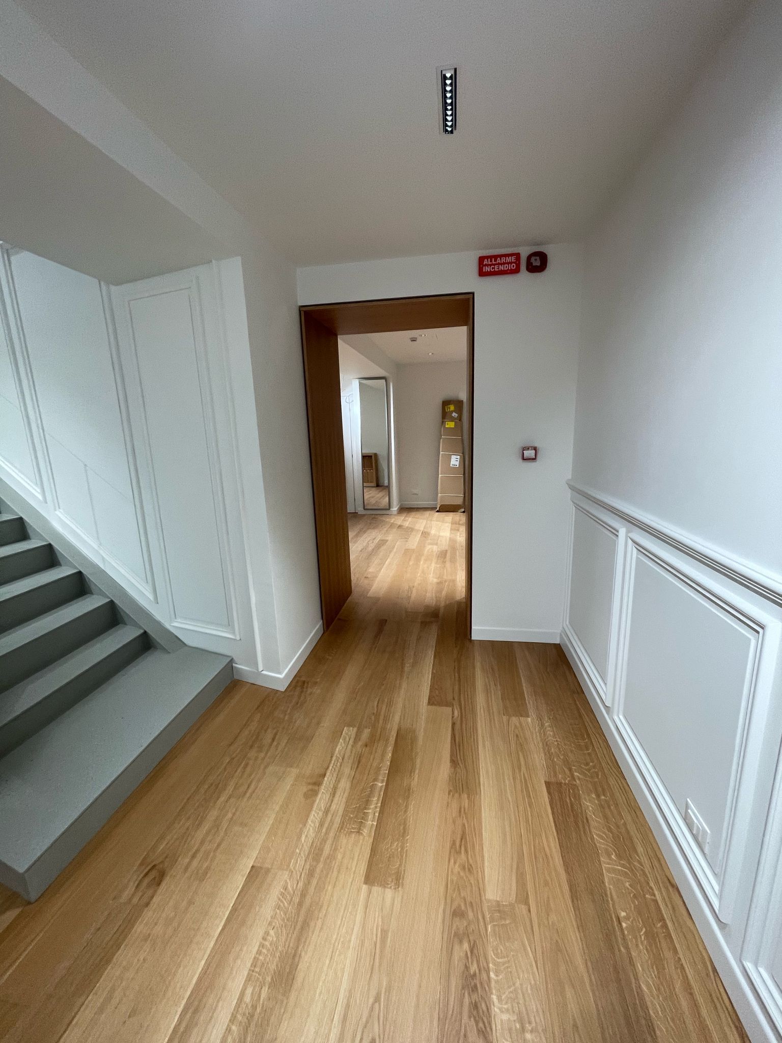 Un corridoio con pavimenti in legno e scale che conducono a una stanza.