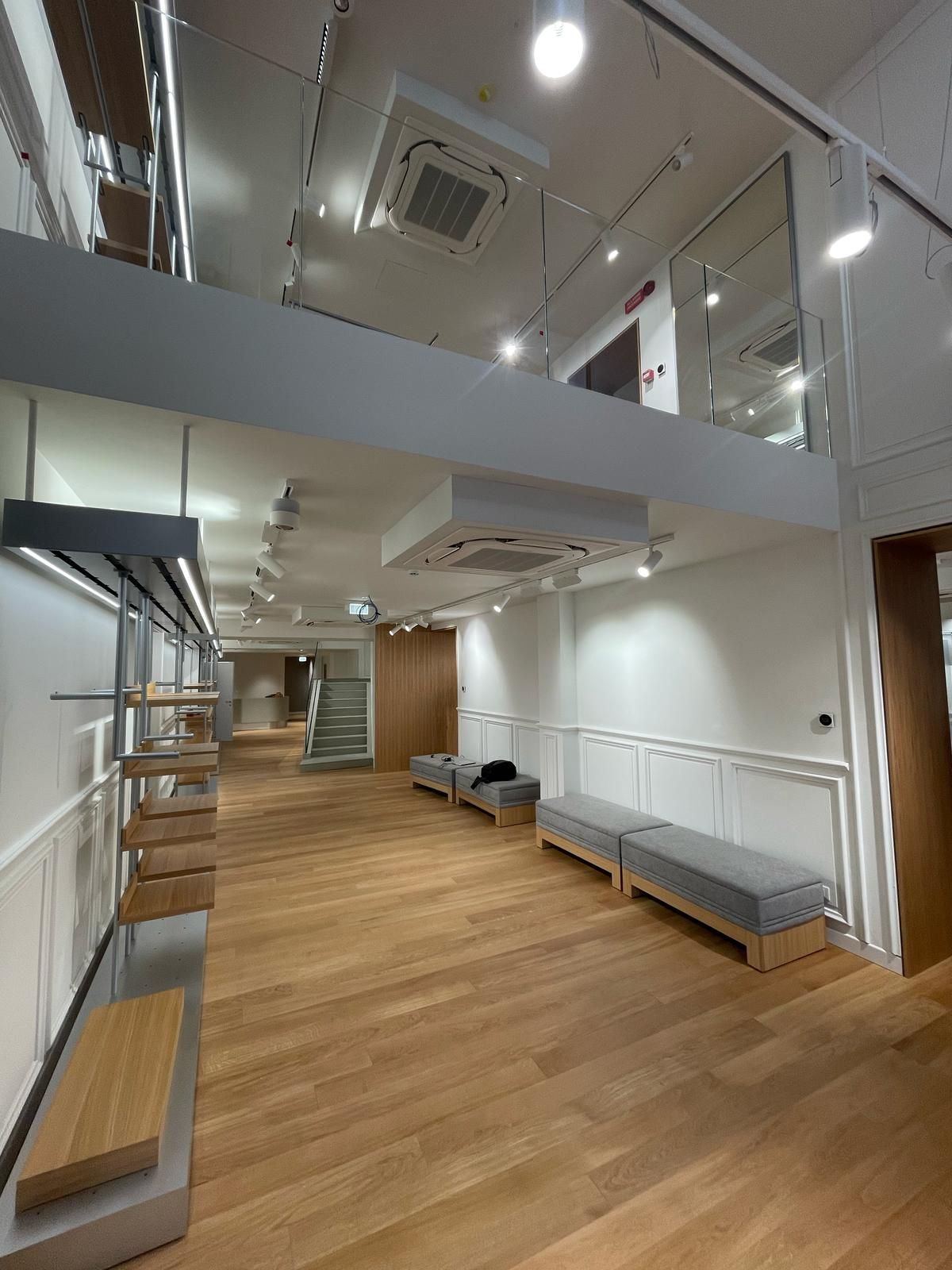 Una grande stanza con pavimenti in legno e scale in un edificio.