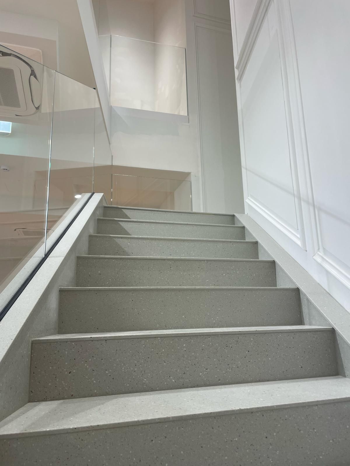 Un primo piano di una rampa di scale con ringhiera in vetro