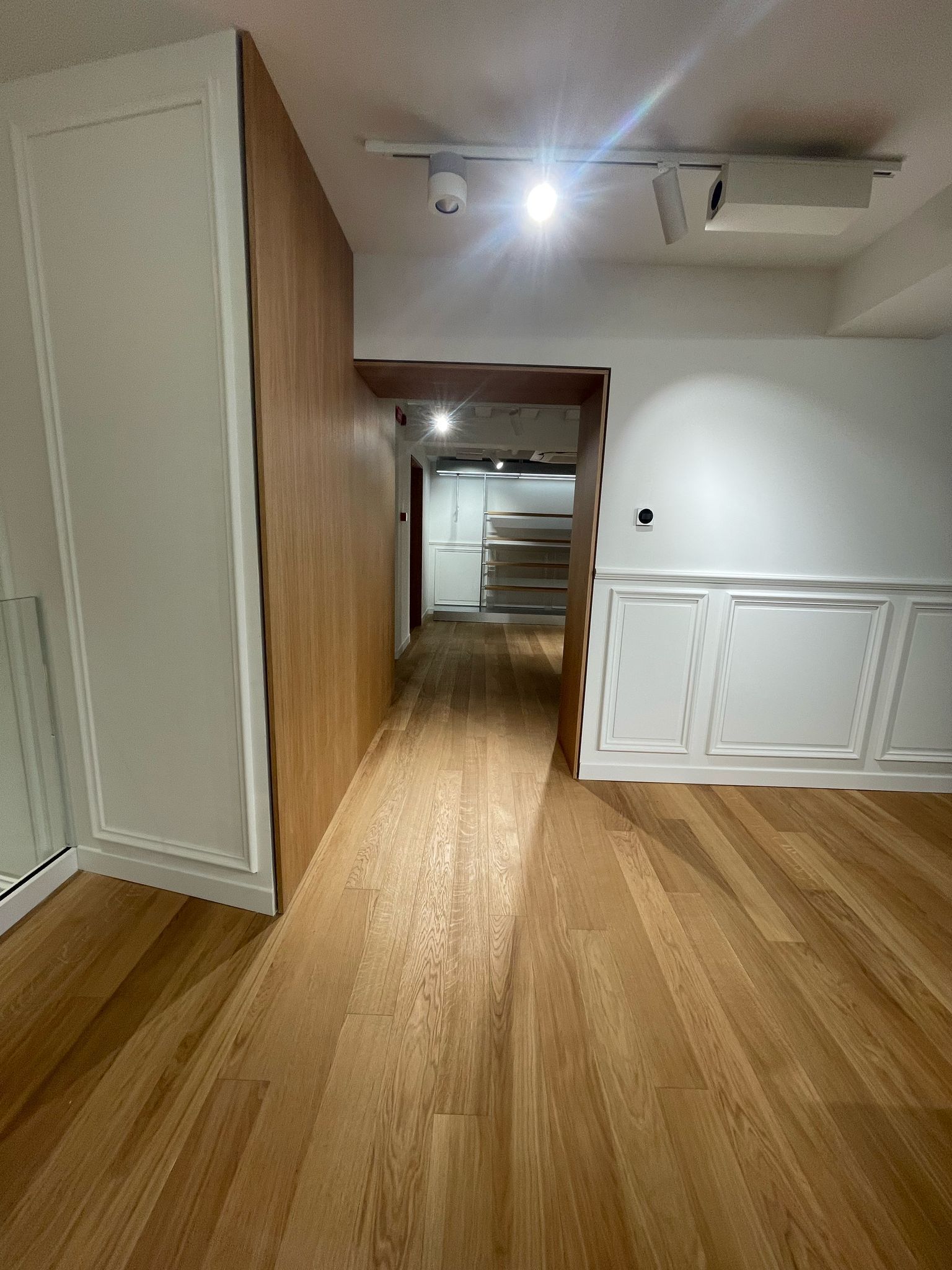 Un corridoio con pavimenti in legno e pareti bianche in una casa.