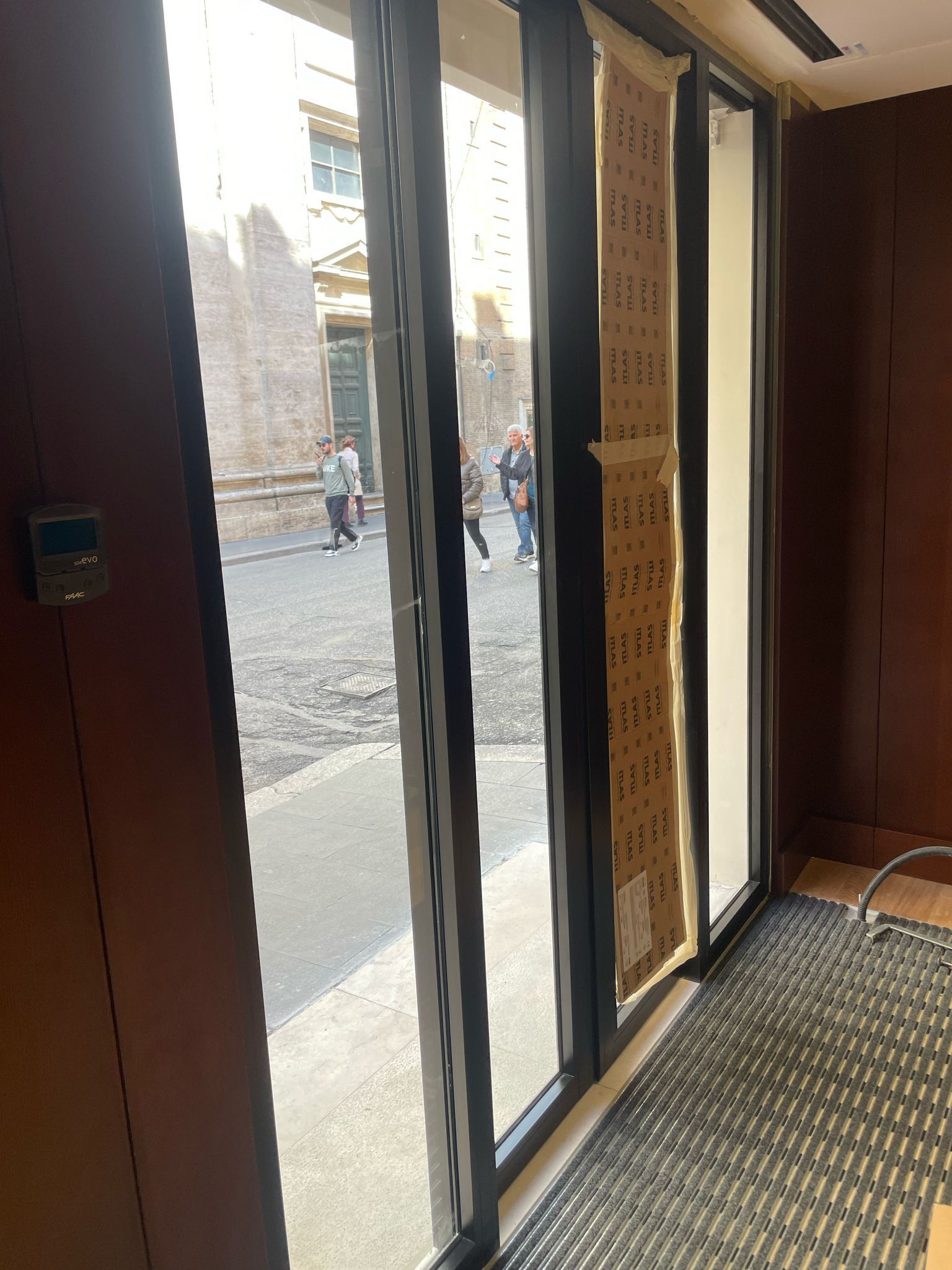 Una stanza con molte finestre e uno zerbino nero sul pavimento.