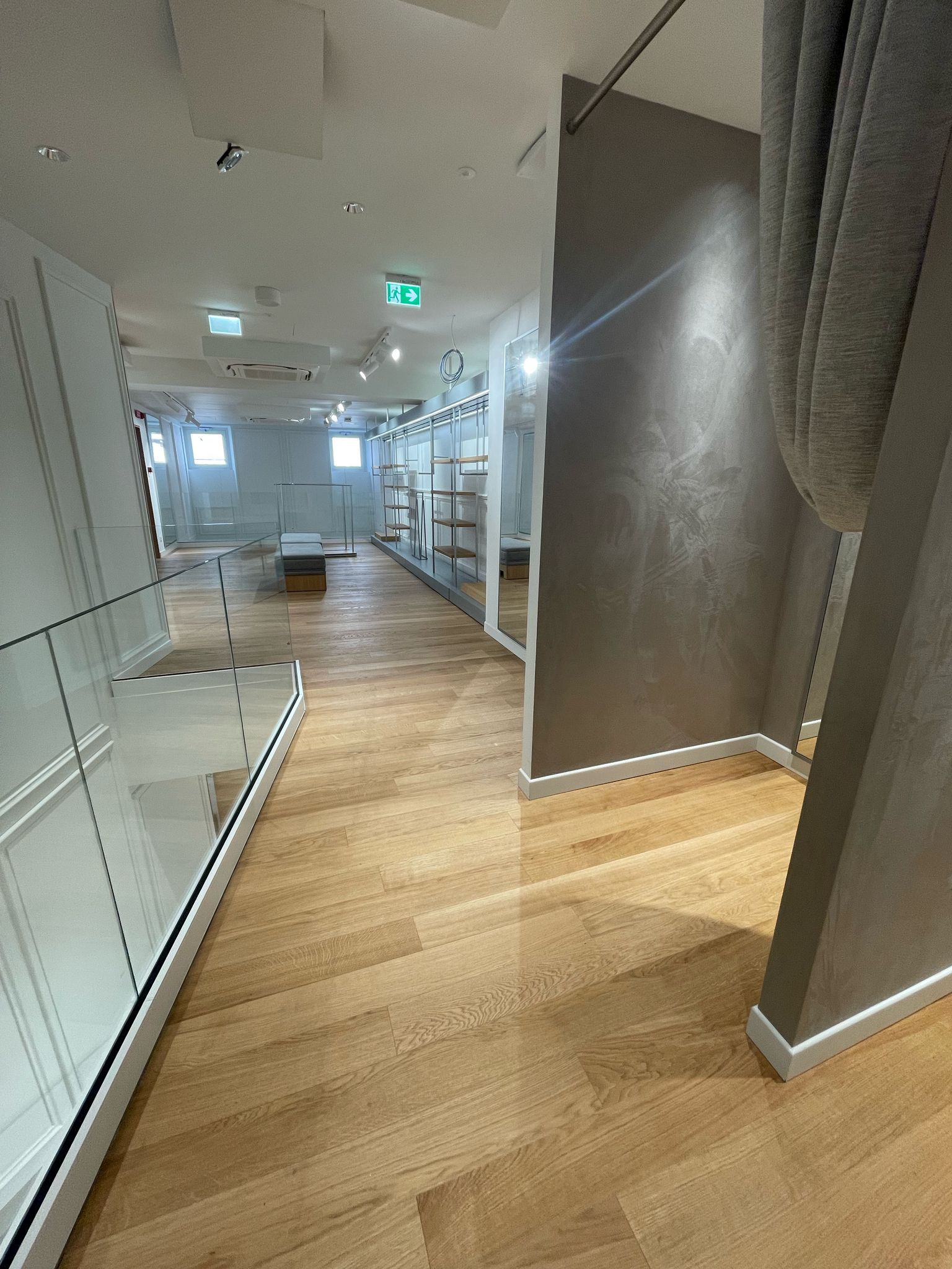 Un lungo corridoio con pavimento in legno e molti specchi.