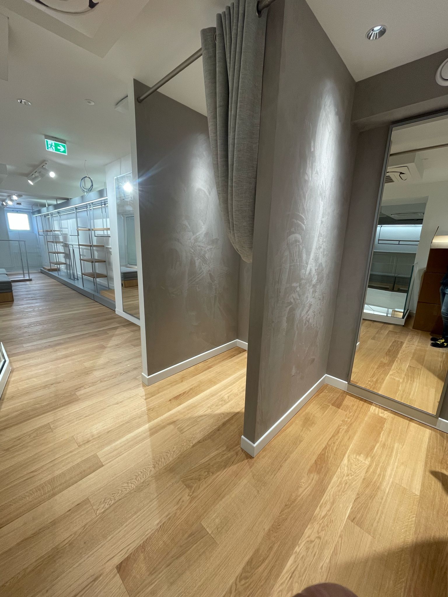 Un camerino in un negozio con pavimenti in legno e specchi.