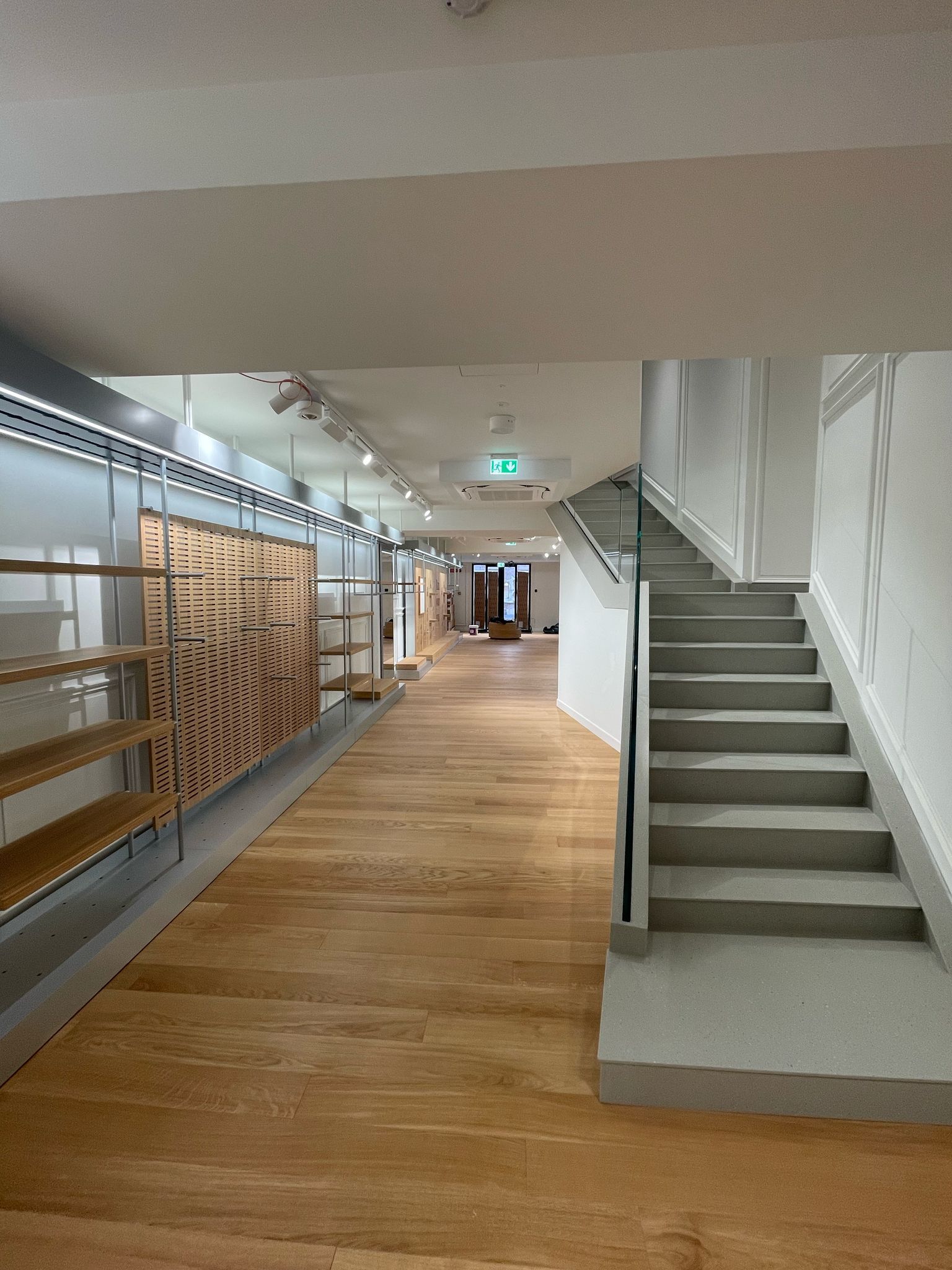 Un lungo corridoio con pavimenti in legno e scale in un edificio.