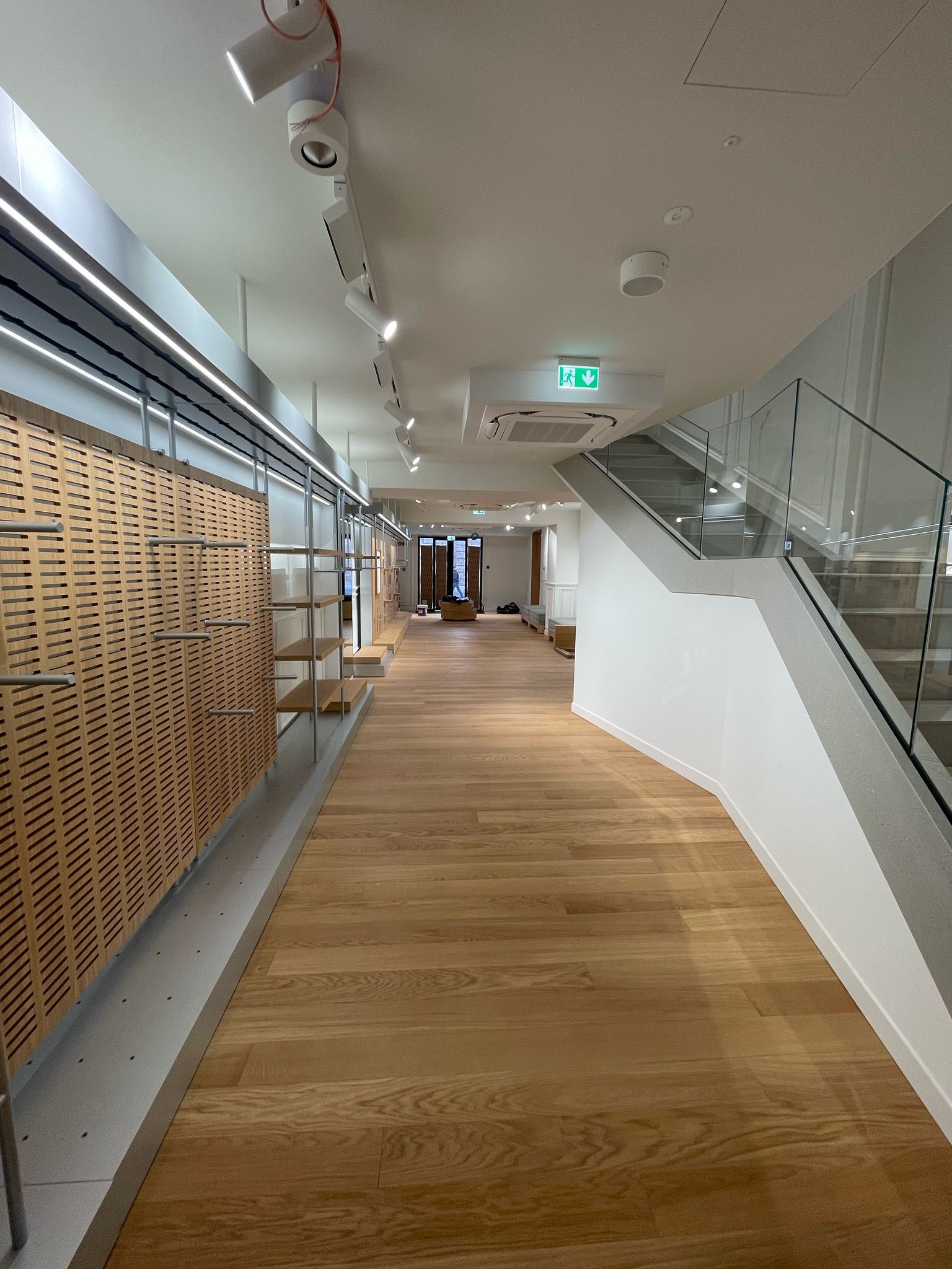 Un lungo corridoio con pavimenti in legno e scale in un edificio.