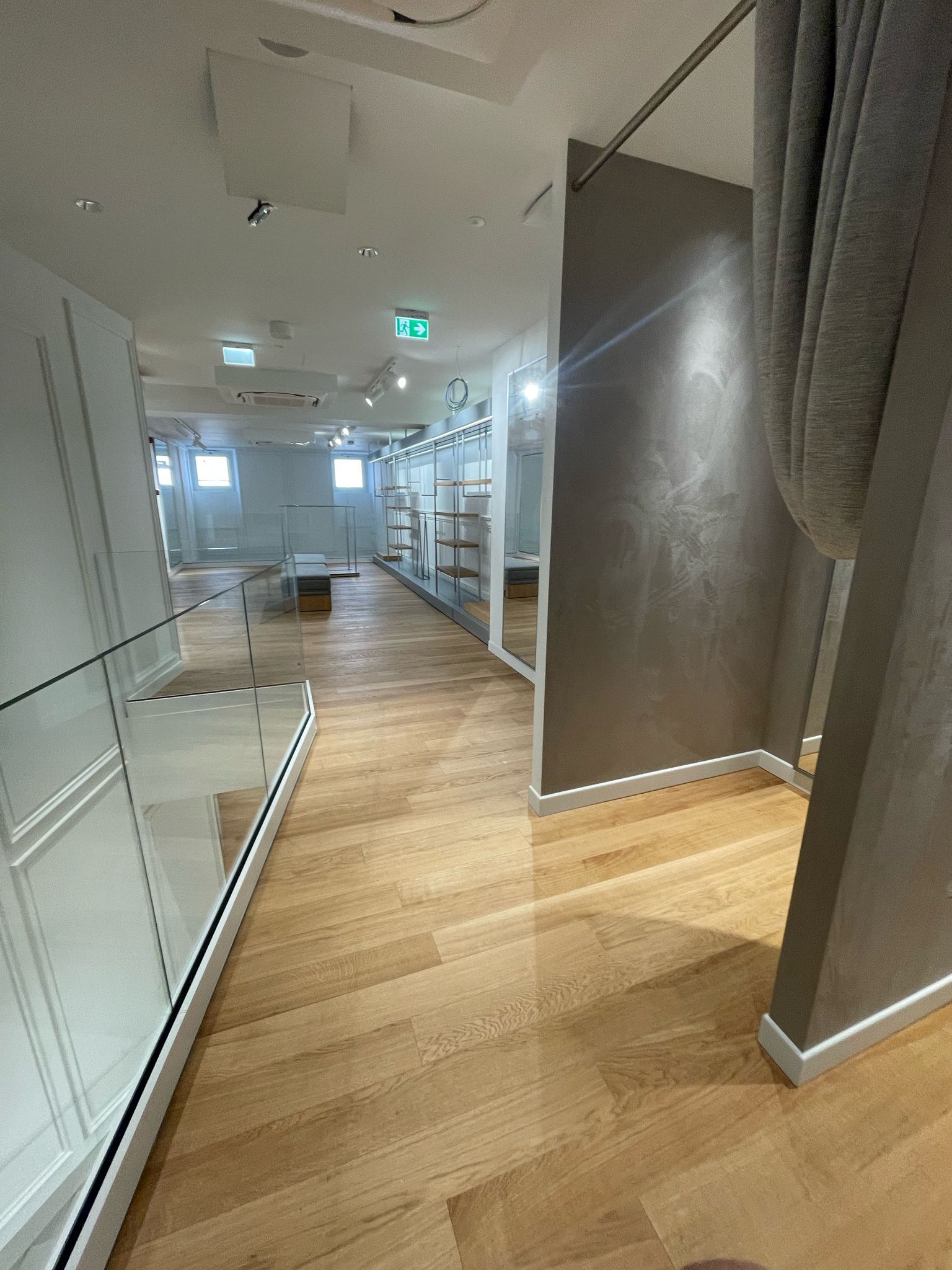 Un camerino in un negozio con pavimenti in legno e specchi.