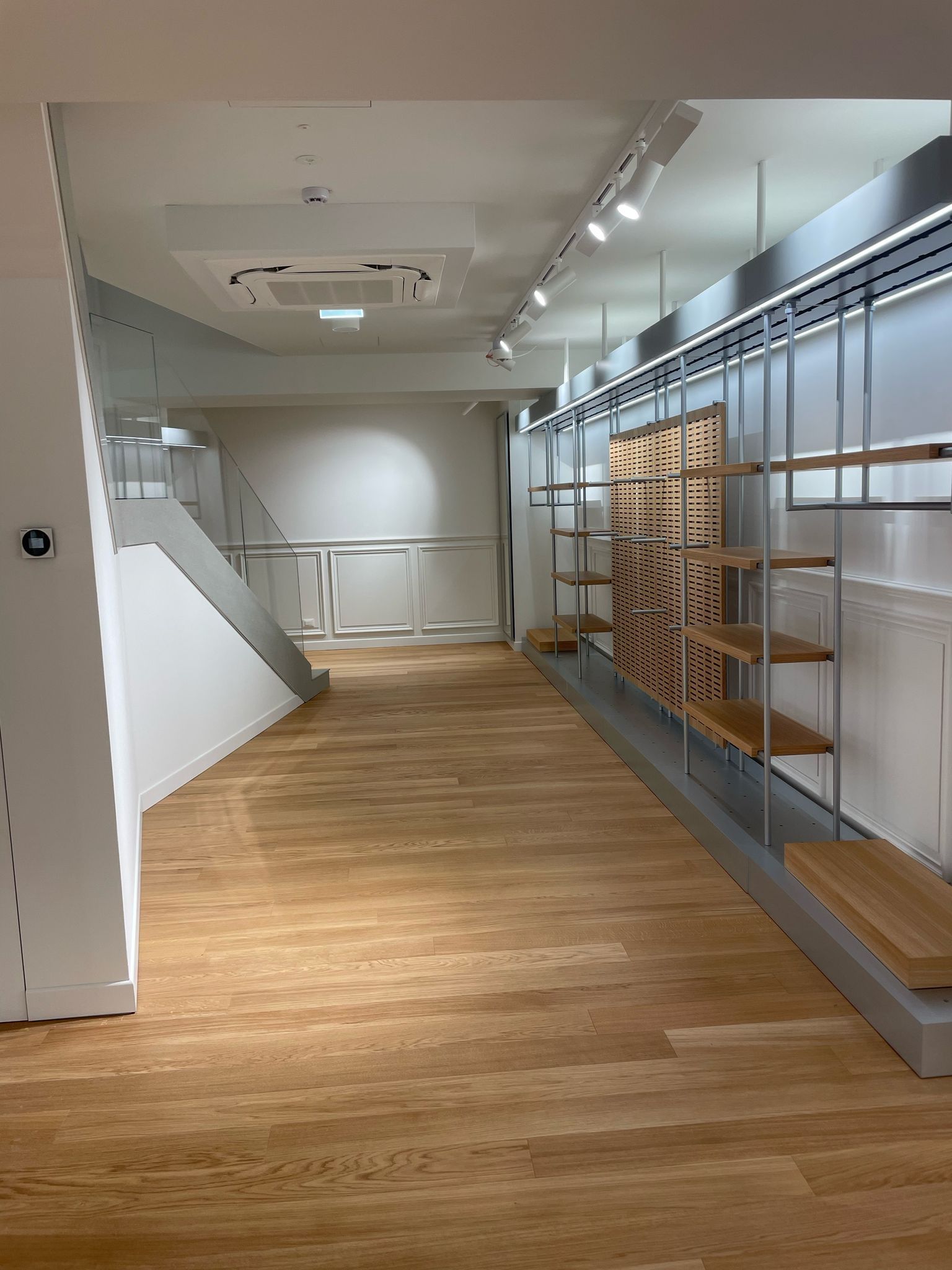 Una grande stanza vuota con pavimenti e scaffali in legno.