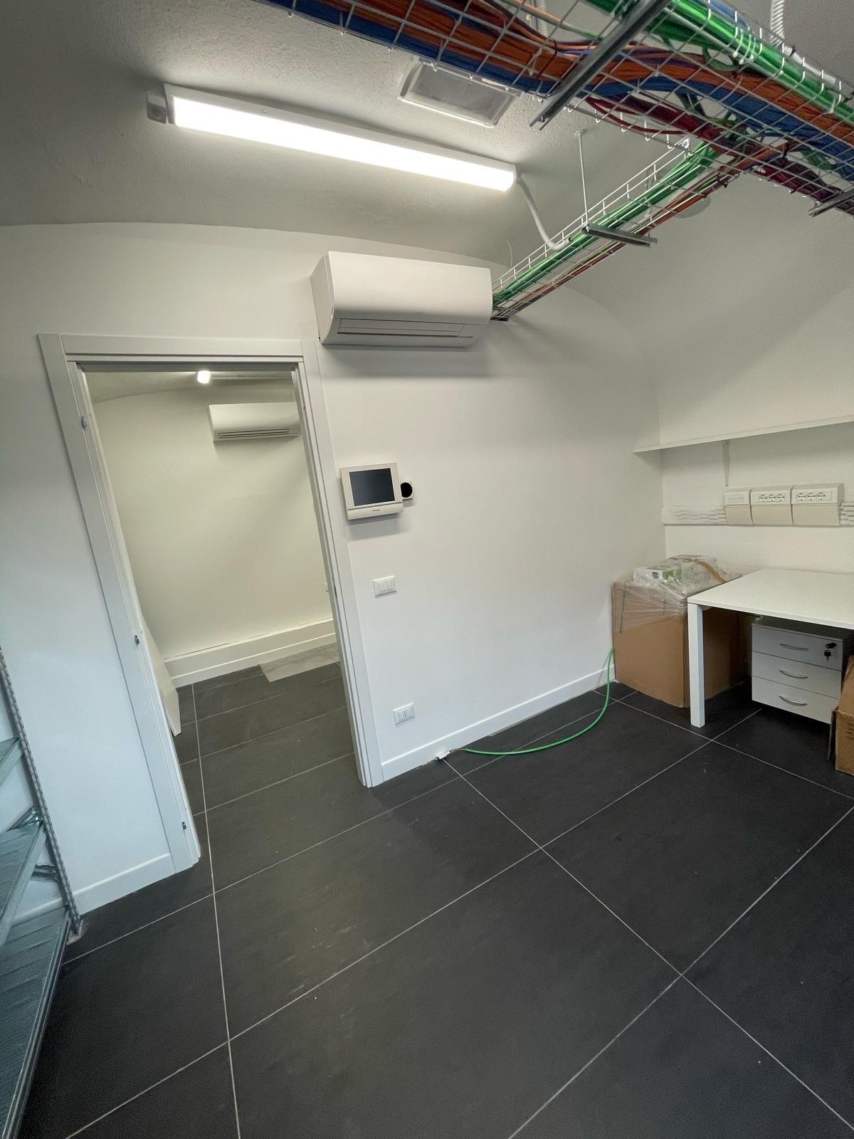 Una stanza con una scrivania e una televisione sul muro.