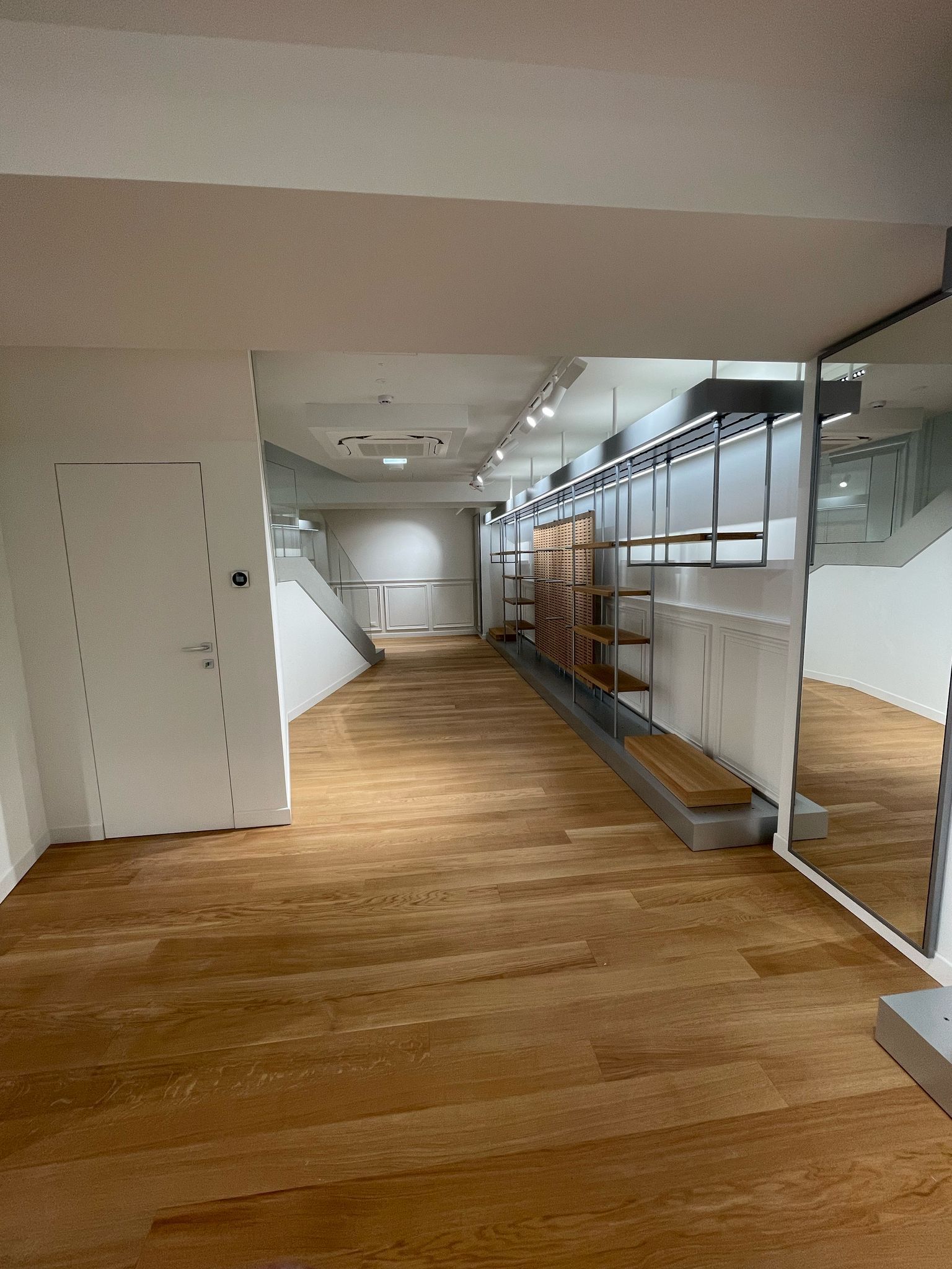 Una grande stanza vuota con pavimenti in legno e uno specchio.