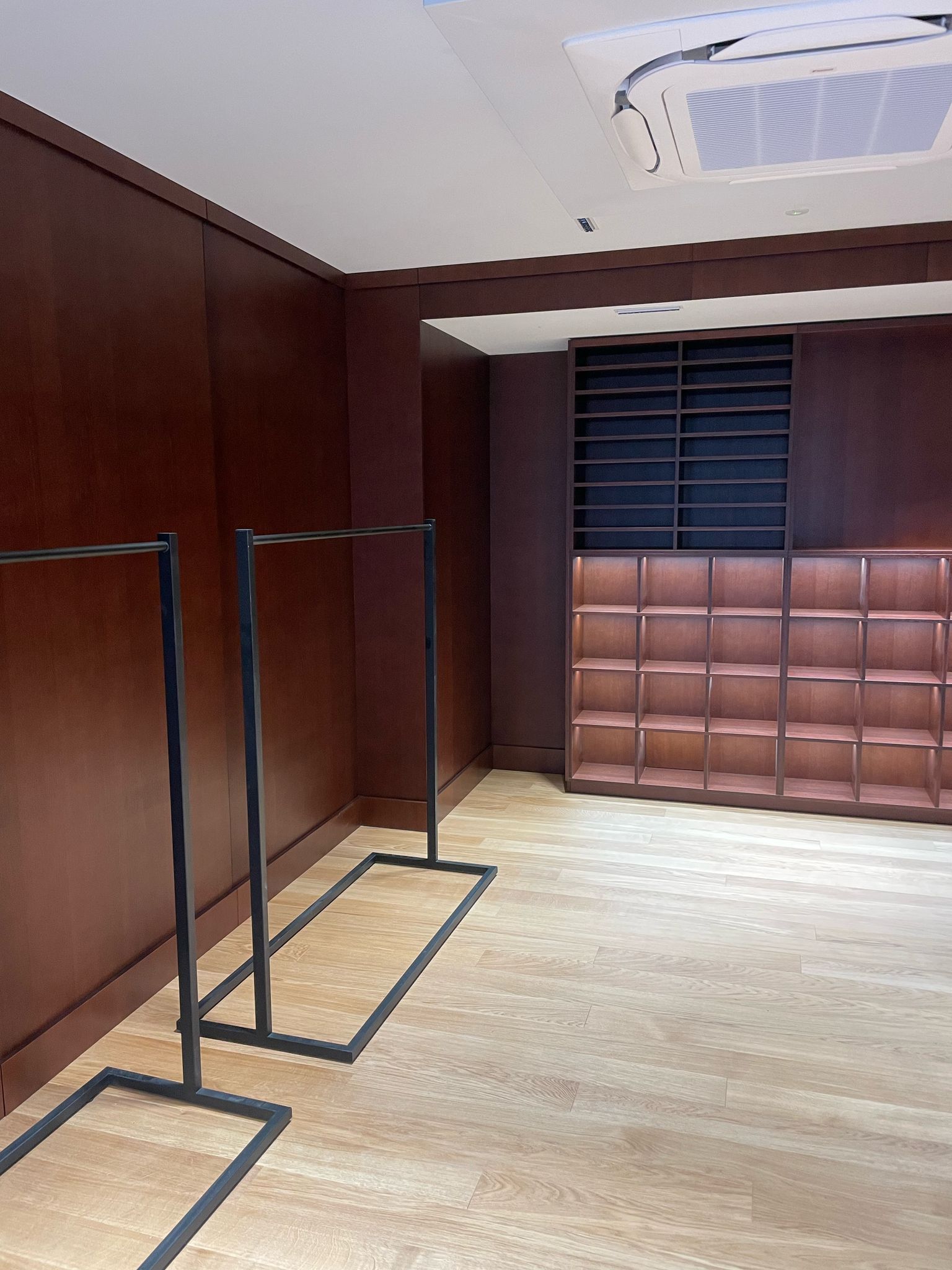 Una stanza vuota con scaffali di legno e attaccapanni.