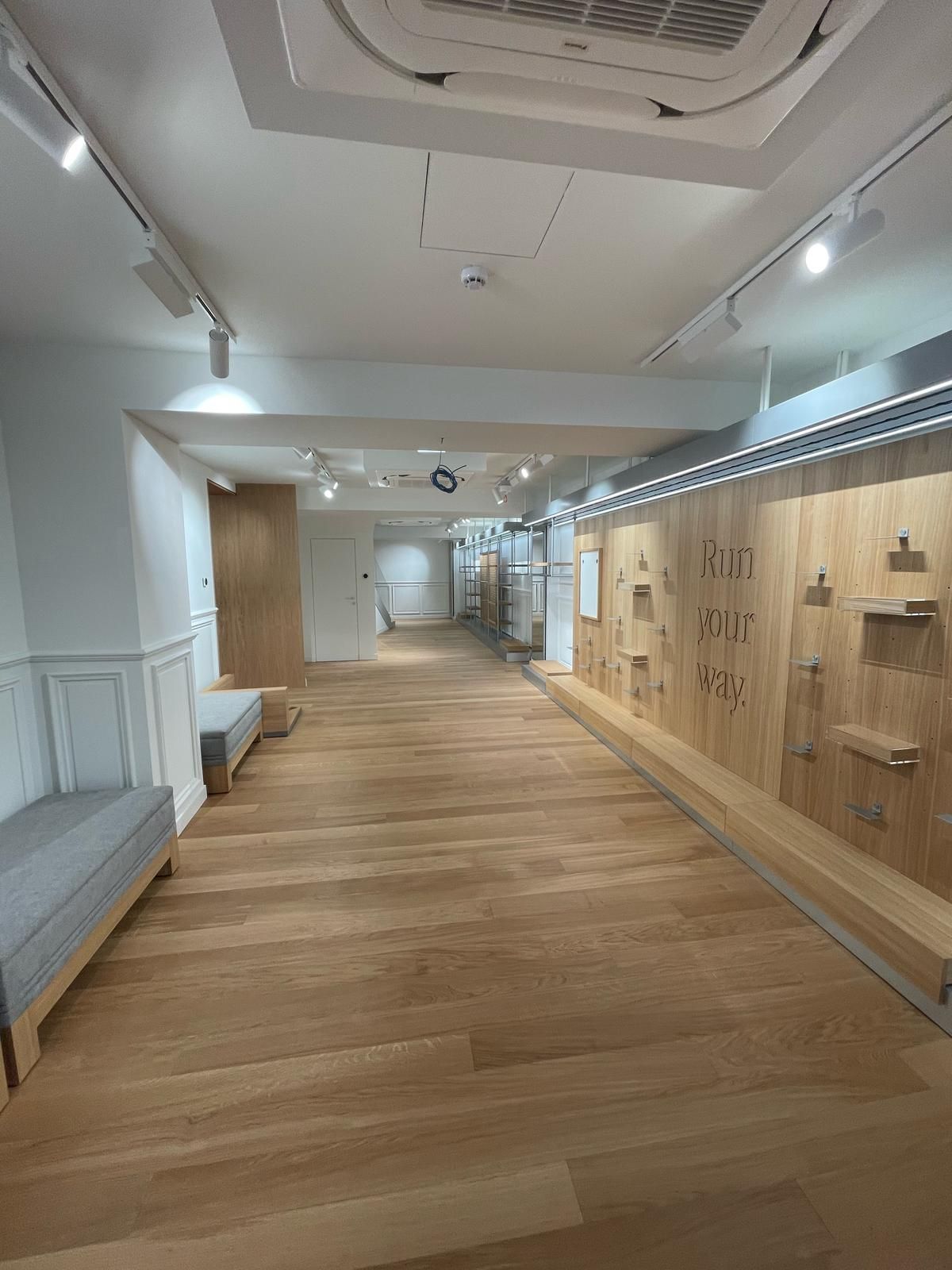 Un lungo corridoio con pavimenti in legno e un ventilatore a soffitto.