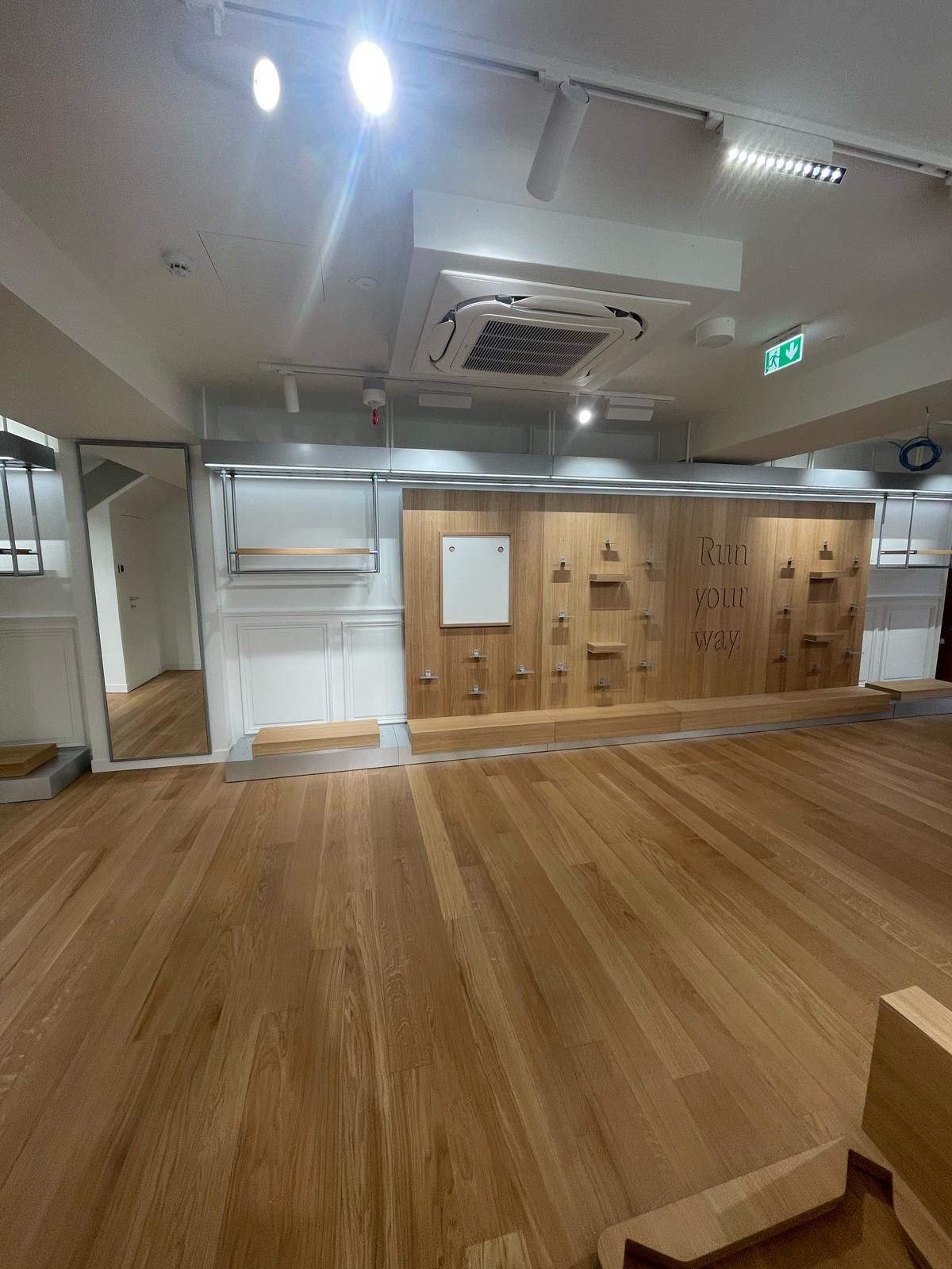 Una grande stanza vuota con pavimenti in legno e una lavagna bianca sul muro.