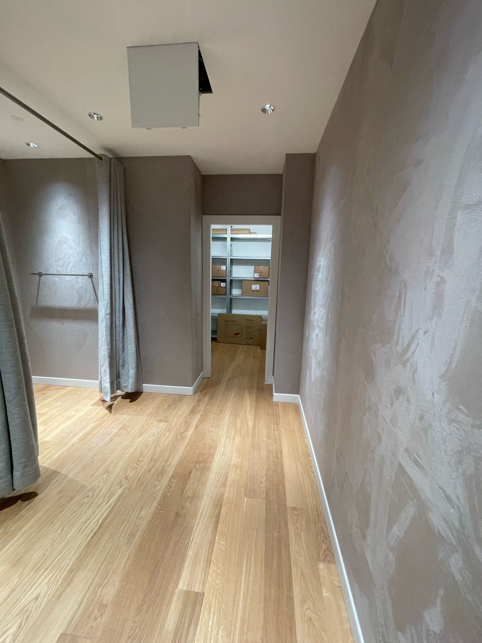 Un lungo corridoio con pavimenti in legno e uno specchio sul soffitto.